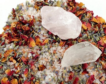 Puede incluir: Primer plano de sales de baño con pétalos de rosa, capullos de lavanda y dos cristales de cuarzo transparentes. Las sales son una mezcla de blanco y rosa, con pétalos de rosa en tonos rojos y naranjas.