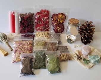 May include: A collection of dried herbs, flowers, and crystals in clear plastic bags and a small glass jar. The items are arranged on a white surface. The items include dried rose petals, lavender, sage, and bay leaves. There are also two pink and red candles, a small white candle, a bundle of sage, and a piece of palo santo wood. The crystals are rose quartz and green aventurine.