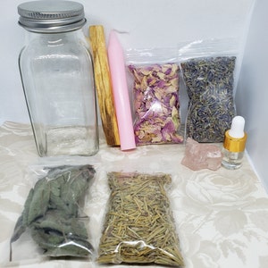 May include: A collection of items for a ritual or spell, including a clear glass bottle with a silver lid, a pink candle, a wooden stick of incense, a bag of dried rose petals, a bag of dried lavender, a small bag of dried herbs, a bag of dried rosemary, a pink crystal, and a small bottle of oil.