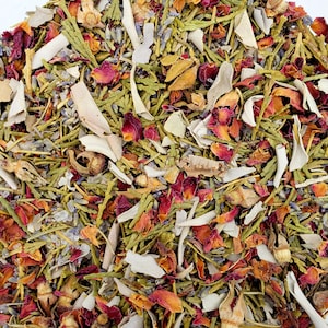 May include: Close-up of a blend of dried herbs and flowers. The mix includes green rosemary, lavender, rose petals, and other dried botanicals. The colors are a mix of green, purple, red, and beige. The image is a top-down view of the blend.