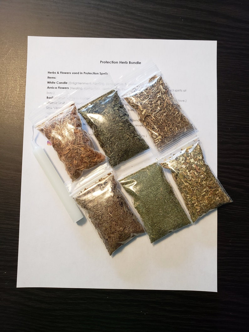 May include: A Protection Herb Bundle with a white candle and several small clear bags filled with dried herbs and flowers. The text "Protection Herb Bundle" is printed on a white sheet of paper.