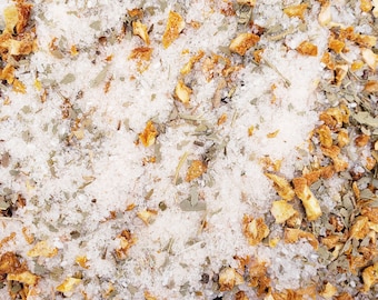 May include: A close-up of a mixture of dried orange peel, herbs, and white salt. The mixture is a light brown color and has a rough texture.
