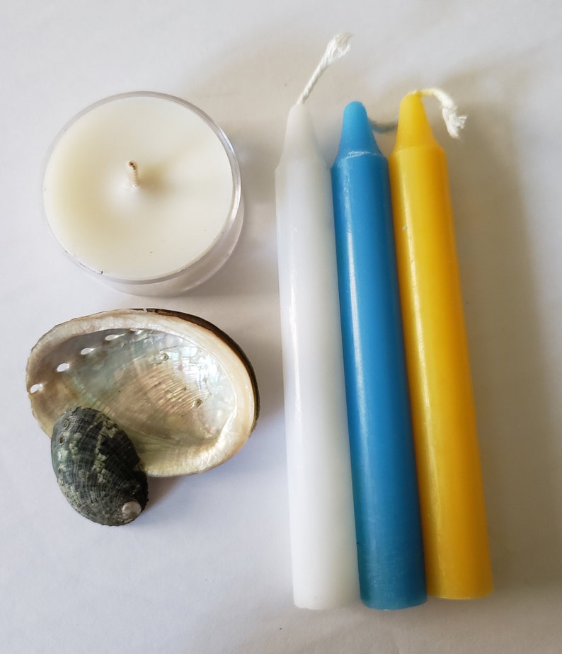 May include: A white, blue, and yellow candle set with a small white tea light candle and a seashell.