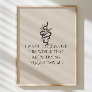 May include: A framed print with a beige background and a black snake illustration. The text reads: "I WANT TO SURVIVE THIS WORLD THAT KEEPS TRYING TO DESTROY ME."