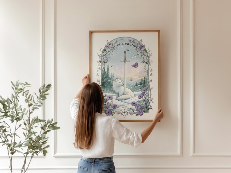 Puede incluir: Una impresi&oacute;n art&iacute;stica enmarcada con una ilustraci&oacute;n en acuarela de un zorro blanco, una espada y el texto "She is moonlight". La obra de arte est&aacute; ambientada en un paisaje nevado con flores moradas y mariposas. El marco es de color marr&oacute;n claro.