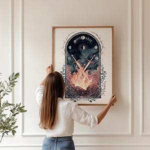 Puede incluir: Una impresi&oacute;n art&iacute;stica enmarcada con una ilustraci&oacute;n de acuarela de tem&aacute;tica celestial. La obra de arte representa espadas cruzadas sobre llamas, con las palabras "world under" en la parte superior. La impresi&oacute;n es sostenida por una persona.