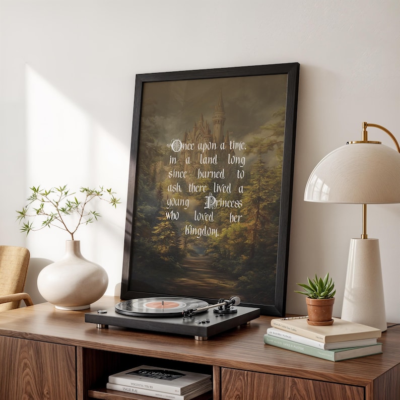 May include: A framed print with the text "Once upon a time, in a land long since burned to ash, there lived a young Princess who loved her kingdom." The print is displayed on a wooden cabinet with a record player and a lamp.