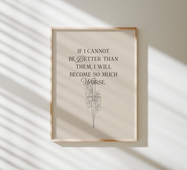 May include: A framed print featuring the quote "IF I CANNOT BE BETTER THAN THEM, I WILL BECOME SO MUCH WORSE." The text is in black, with a floral and dagger illustration. The frame is a light wood colour.