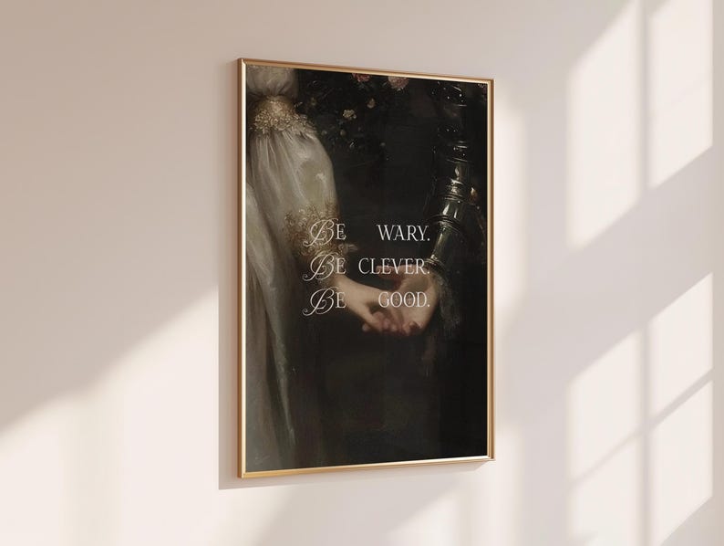 Puede incluir: Un cuadro enmarcado con una pintura de estilo vintage de dos figuras tomadas de la mano. La obra de arte tiene una est&eacute;tica oscura y melanc&oacute;lica con detalles dorados y el texto "Be wary. Be clever. Be good."