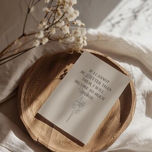 May include: A wooden bowl contains a card with the text "IF I CANNOT BE BETTER THAN THEM, I WILL BECOME SO MUCH WORSE." The card features a floral illustration. Dried white flowers are in the background.