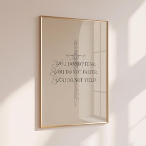 Może przedstawiać: Oprawiony wydruk ze złotą ramą, przedstawiający ilustrację miecza i tekst "YOU DO NOT FEAR. YOU DO NOT FALTER. YOU DO NOT YIELD." Grafika jest wyświetlana na beżowym tle.