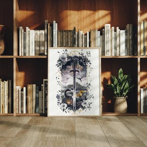 以下が含まれることがあります： 剣、ドラゴン、風景の水彩イラストが描かれた、額入りのアートプリント。 アートワークは花の要素と「about little things」のテキストで囲まれています。 プリントは木製の本棚に飾られています。