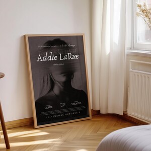 K&ouml;nnte beinhalten: Ein Filmplakat f&uuml;r den Film "The Remarkable Life of Addie LaRue", Regie: Diane English. Das Plakat zeigt ein Schwarzwei&szlig;bild eines Frauen Gesichts mit dem Titel des Films in wei&szlig;er Schrift. Das Plakat enth&auml;lt auch die Namen der Schauspieler und das Erscheinungsdatum.