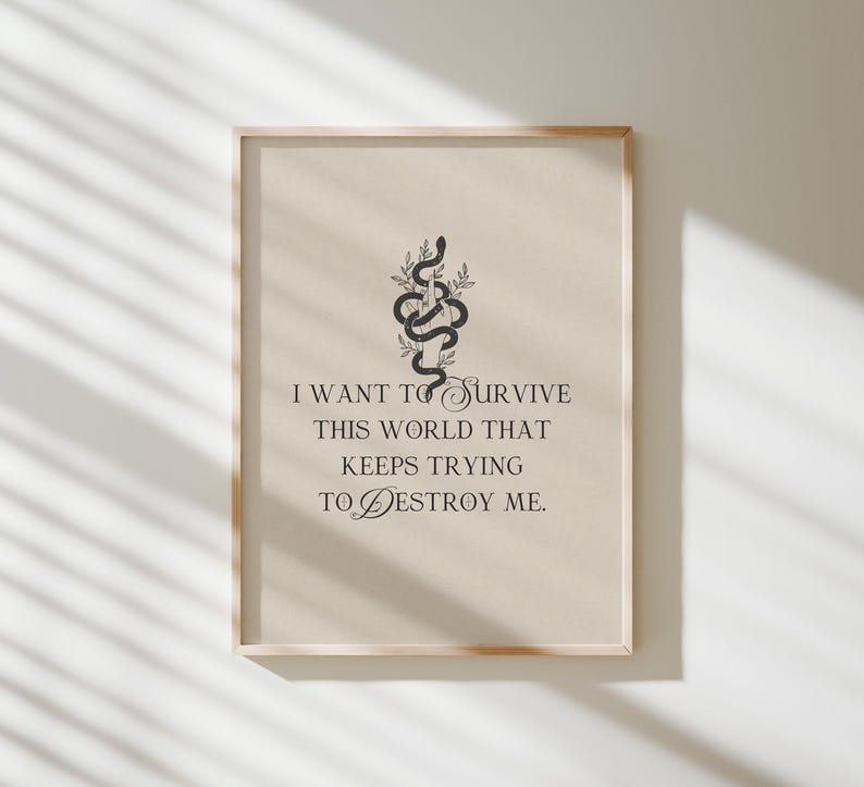 May include: A framed print with a beige background and a black snake illustration. The text reads: "I WANT TO SURVIVE THIS WORLD THAT KEEPS TRYING TO DESTROY ME."
