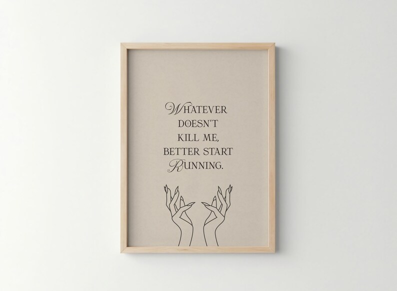 May include: Framed art print with a light beige background and a wooden frame. The print features the quote "Whatever doesn't kill me, better start running" in elegant script, with a line drawing of hands at the bottom.