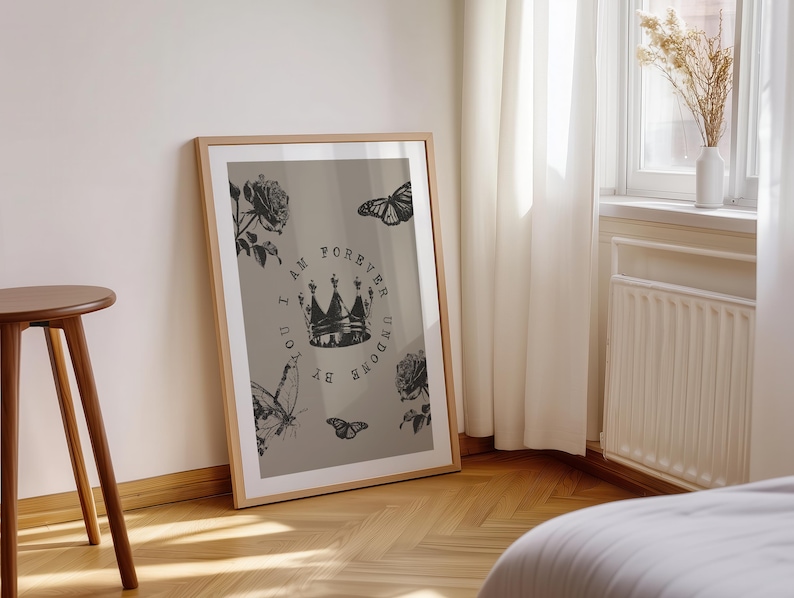 May include: A framed art print featuring a crown design with the text "I AM FOREVER UNDONE BY YOU". The artwork includes illustrations of roses and butterflies in black and white against a neutral background. The frame is a light wood color.