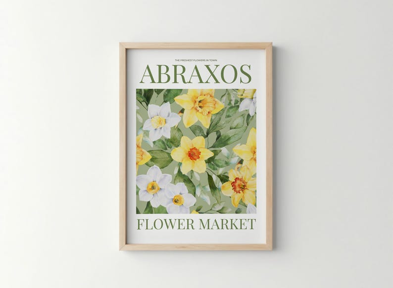 Puede incluir: Una impresi&oacute;n art&iacute;stica enmarcada con un dise&ntilde;o floral de narcisos amarillos y blancos y hojas verdes. El texto "ABRAXOS" y "FLOWER MARKET" est&aacute; impreso en verde. La impresi&oacute;n est&aacute; en un marco de madera clara.