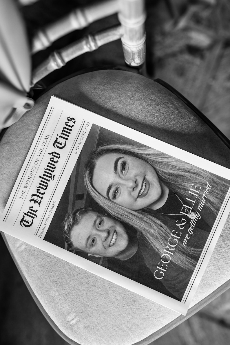 May include: Black and white photograph of a newspaper titled "The Newlywed Times" with the headline "The Wedding of the Year." The newspaper features two smiling people and the text "GEORGE & ELLIE are getting married" and "16th August 2025."