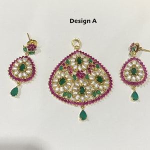 May include: A gold pendant necklace set with pink and green gemstones. The pendant is shaped like a teardrop and features a floral design. The earrings are small and round, with a similar floral design.