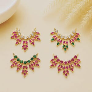 May include: Four gold-toned jewelry connectors shaped like fan-like leaves, each featuring a row of clear stones at the top and marquise-cut stones in pink or green arranged in a cascading pattern, designed with two small loops for attachment.