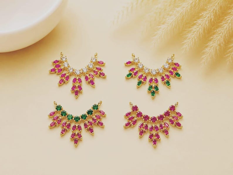 May include: Four gold-toned jewelry connectors shaped like fan-like leaves, each featuring a row of clear stones at the top and marquise-cut stones in pink or green arranged in a cascading pattern, designed with two small loops for attachment.