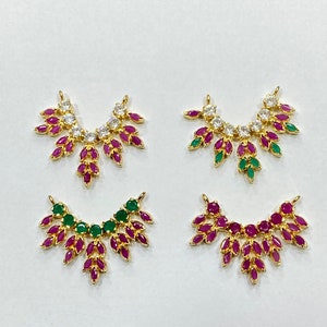 May include: Four gold-tone jewelry connectors in a fan-like shape. Each piece features marquise-cut stones in various color combinations, including clear, pink, and green, arranged in a symmetrical pattern with two small loops at the top edges.
