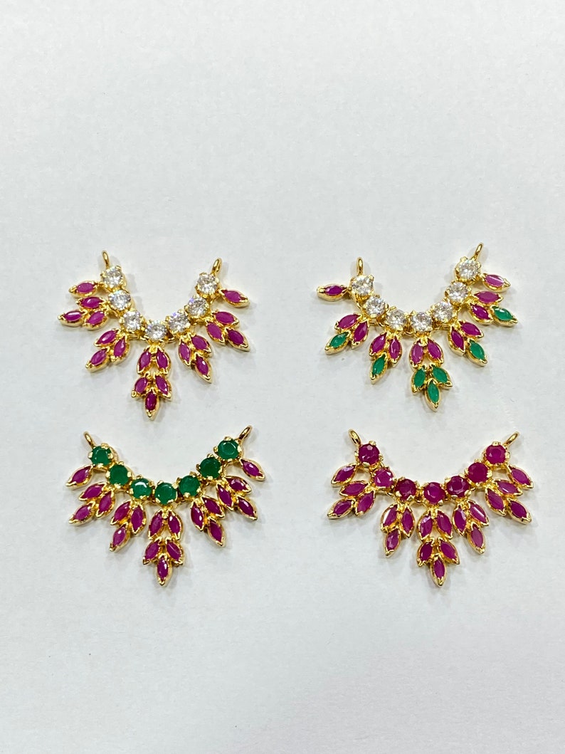 May include: Four gold-tone jewelry connectors in a fan-like shape. Each piece features marquise-cut stones in various color combinations, including clear, pink, and green, arranged in a symmetrical pattern with two small loops at the top edges.