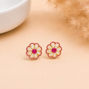 Puede incluir: Un par de pendientes de botón dorados con forma de flor. Cada pendiente presenta una piedra preciosa rosa redonda en el centro, rodeada por un anillo de perlas blancas en forma de lágrima y un borde exterior de pequeñas piedras rosas.