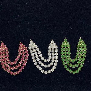 May include: Three strands of decorative jewelry with flower-shaped beads. The strands are in red, white, and green.