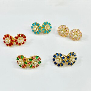 May include: A set of ten gold-tone earrings with pearl accents. Each pair features a different colored gemstone: red, blue, pink, green, and turquoise.