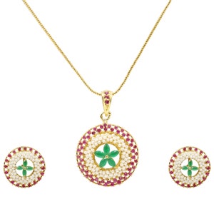 May include: A gold necklace with a pendant featuring a green flower surrounded by white pearls and red stones. Matching earrings with the same design.