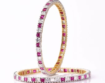 Könnte beinhalten: Zwei goldene Armreifen mit einer Reihe von quadratischen rosa und weißen Steinen.