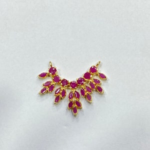 May include: A gold-toned jewelry connector labeled DESIGN C, featuring a symmetrical arrangement of vibrant fuchsia-pink marquise and round-cut stones set in a leaf-like pattern with two small loops at the top for attachment to chains or cords.