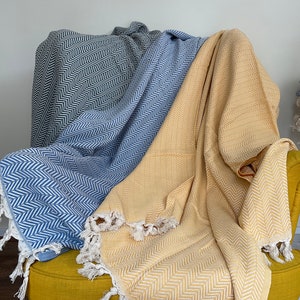 May include: Two woven throw blankets with fringe, one blue and one yellow, draped over a yellow armchair.