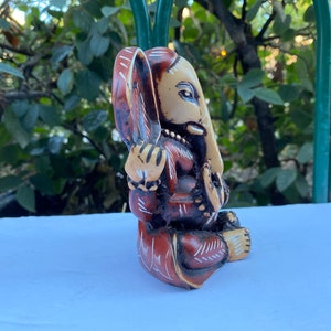 K&ouml;nnte beinhalten: Eine kleine, handbemalte Holzfigur von Ganesha, dem hinduistischen Gott der Weisheit und des Wohlstands. Die Figur ist in Braun-, Rot- und Wei&szlig;t&ouml;nen bemalt und weist komplizierte Details auf.
