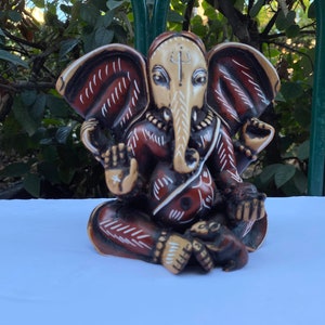 K&ouml;nnte beinhalten: Eine braun-wei&szlig; bemalte Figur des hinduistischen Gottes Ganesha. Die Figur sitzt mit gekreuzten Beinen und erhobenem R&uuml;ssel. Die Figur hat ein wei&szlig;es Gesicht mit schwarzen Augen und einen rot-wei&szlig; gemusterten K&ouml;rper.