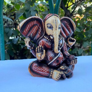 K&ouml;nnte beinhalten: Eine braun-wei&szlig; bemalte Figur des hinduistischen Gottes Ganesha. Die Figur sitzt mit gekreuzten Beinen und erhobenem R&uuml;ssel. Die Figur hat ein rot-wei&szlig;es Muster auf ihrem K&ouml;rper.
