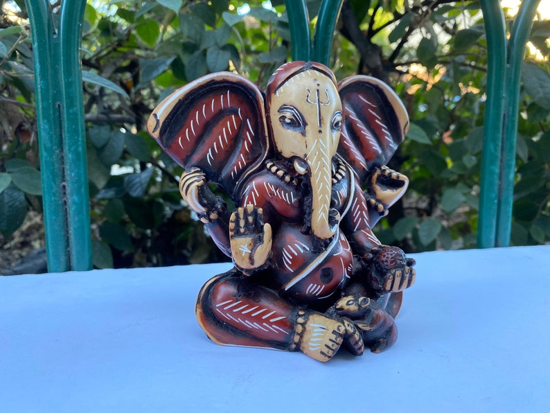 K&ouml;nnte beinhalten: Eine braun-wei&szlig; bemalte Figur des hinduistischen Gottes Ganesha. Die Figur sitzt mit gekreuzten Beinen und erhobenem R&uuml;ssel. Die Figur hat ein rot-wei&szlig;es Muster auf ihrem K&ouml;rper.