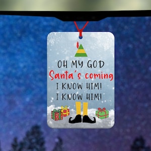 May include: A rectangular Christmas ornament with the text "OH MY GOD Santa's coming I KNOW HIM! I KNOW HIM!" in red and black. The ornament features an elf hat, legs, and presents. It hangs from a red string.