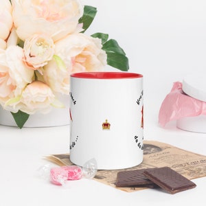 May include: White ceramic mug with a red rim. The mug has a black and white illustration of a crown and the text "You'll never get da... da da da... back".