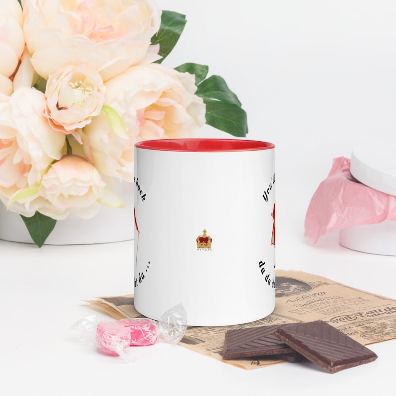 May include: White ceramic mug with a red rim. The mug has a black and white illustration of a crown and the text "You'll never get da... da da da... back".