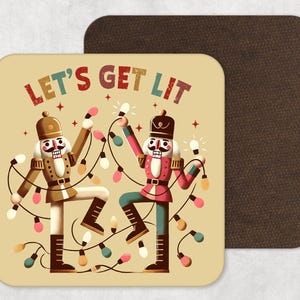 Puede incluir: Un posavasos cuadrado beige con esquinas redondeadas con dos cascanueces de dibujos animados sosteniendo luces de cadena. El texto "LET'S GET LIT" está encima de los cascanueces. Un segundo posavasos marrón está detrás del primero.