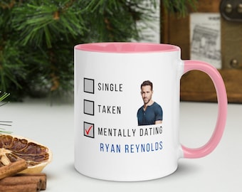 Może przedstawiać: Biały kubek ceramiczny z różowym rantem i uchwytem. Kubek ma listę kontrolną z opcjami "Single", "Zajęty" i "Mentalnie randkujący z Ryanem Reynoldsem". Opcja "Mentalnie randkujący z Ryanem Reynoldsem" jest zaznaczona.