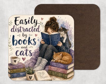 May include: Square coaster with a watercolor illustration of a person reading a book with two cats. The text reads "Easily distracted by books and cats." A cup of coffee and a notepad are also visible.