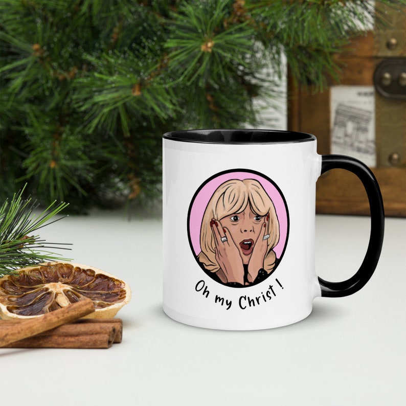 May include: White ceramic mug with a black handle and interior. The mug features a cartoon illustration of a surprised woman inside a pink circle, with the text "Oh my Christ!"