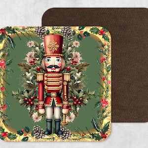 May include: Square coaster with a festive nutcracker soldier design. The nutcracker is in a red uniform with gold details, set against a green background with holly and pinecones. A second brown coaster is visible.