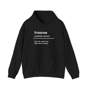Op de afbeelding: Zwarte hoodie met het woord "Potatoes" in het wit, met fonetische spelling en een definitie. De definitie luidt: "Boil 'em, mash 'em, stick 'em in a stew."
