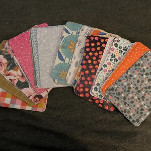 May include: A collection of 14 patterned cards with various floral, geometric, and abstract designs. The cards are arranged in a fan shape, with the top card being a white card with a gray pattern.