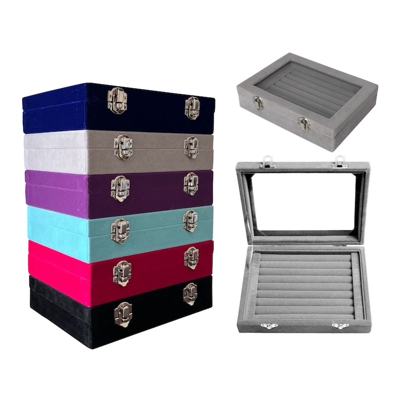 May include: Stack of six ring boxes with velvet lining and a clear lid. The boxes are in various colors including navy blue, gray, purple, light blue, red, and black.