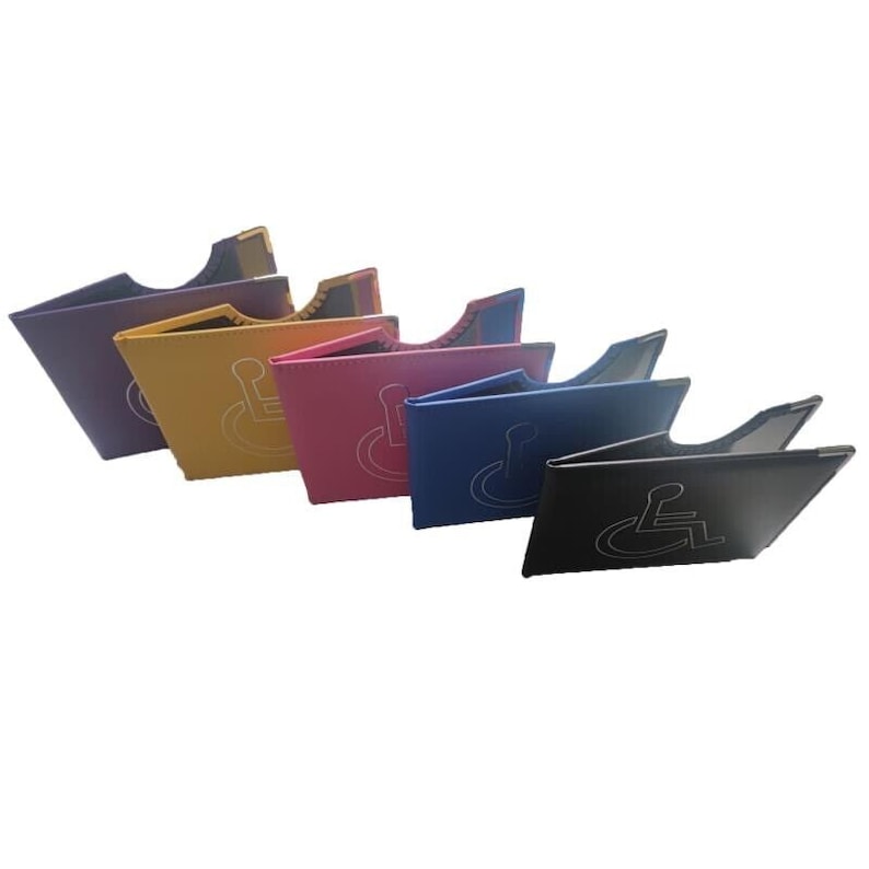 May include: Five different colored wallet-sized card holders with a white wheelchair symbol on the front. The colors are purple, yellow, pink, blue, and black.
